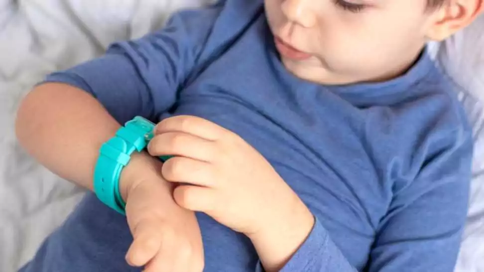 kid using smartwatch blue color lying on bed home interior
