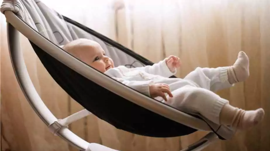 cute smiling baby laying in bouncer chair child relaxing in a swing