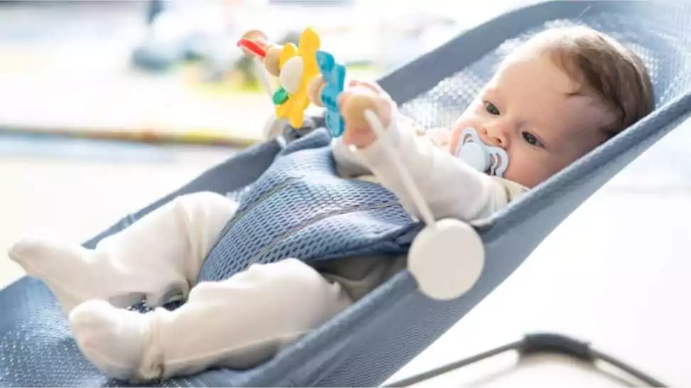 adorable 5 months old baby boy sitting in his bouncer