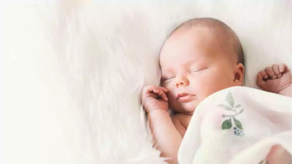 sleeping newborn baby in a wrap on white blanket