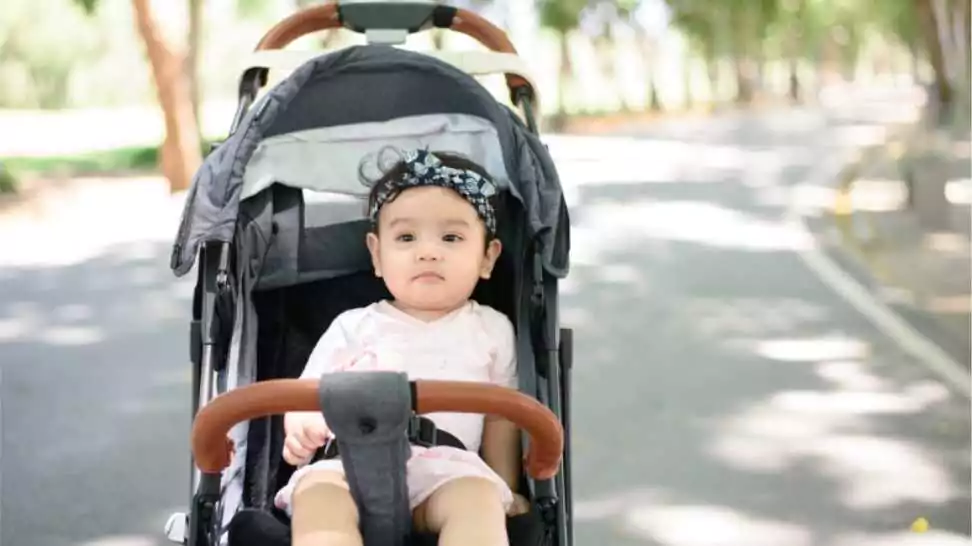 baby sitting in a stroller blurred background of a shady public garden