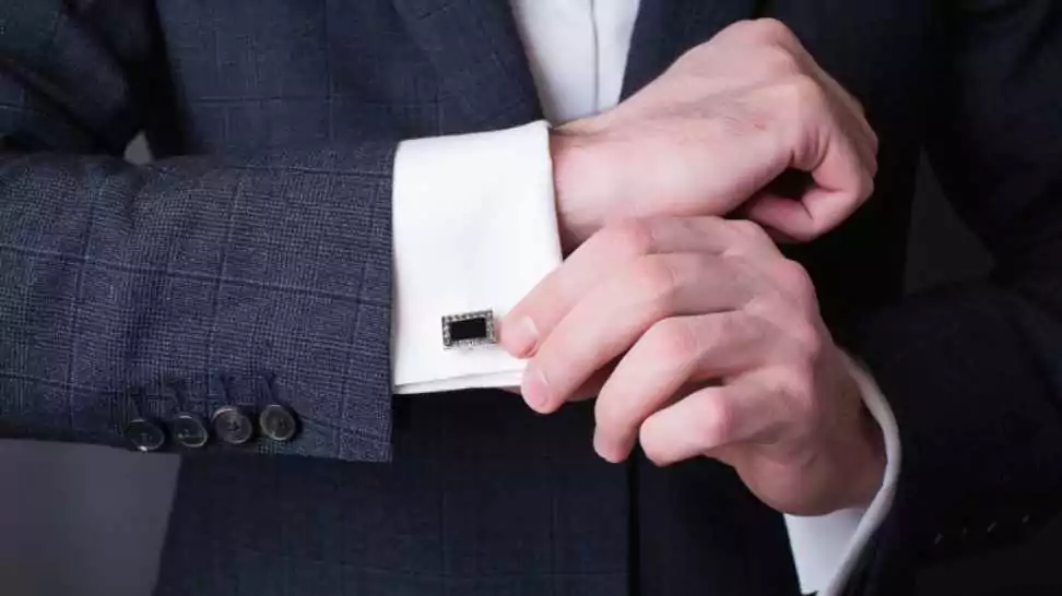 close up of a man in a tuxedo fixing his cufflink