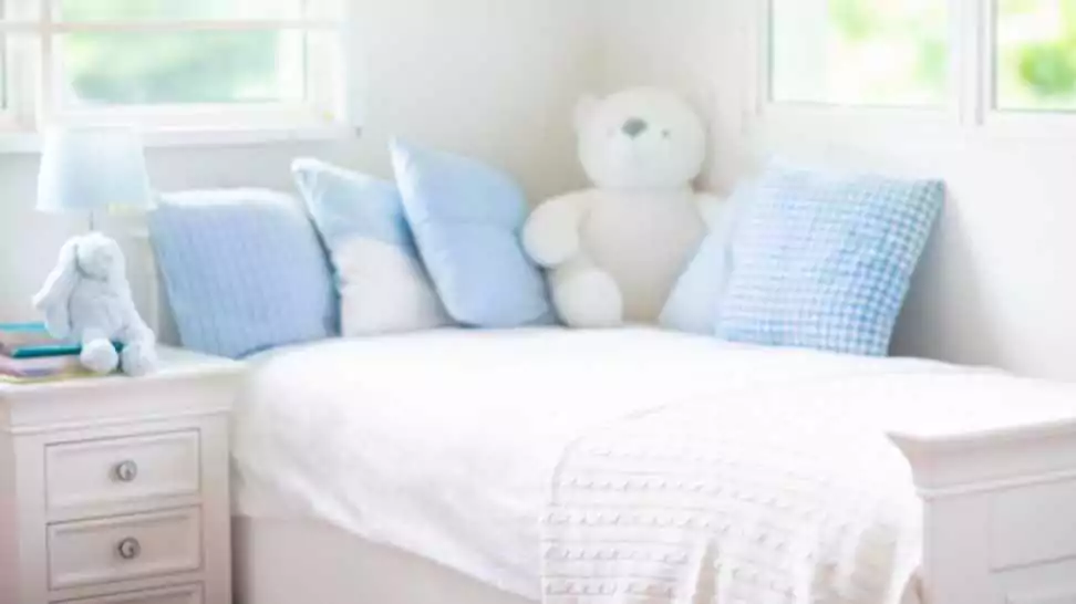 toddler's bed in white sunny bedroom with window