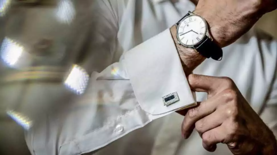 close up of man's hand fastening a cuff before getting married