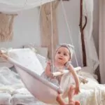 adorable baby girl lying in a linen handmade swing