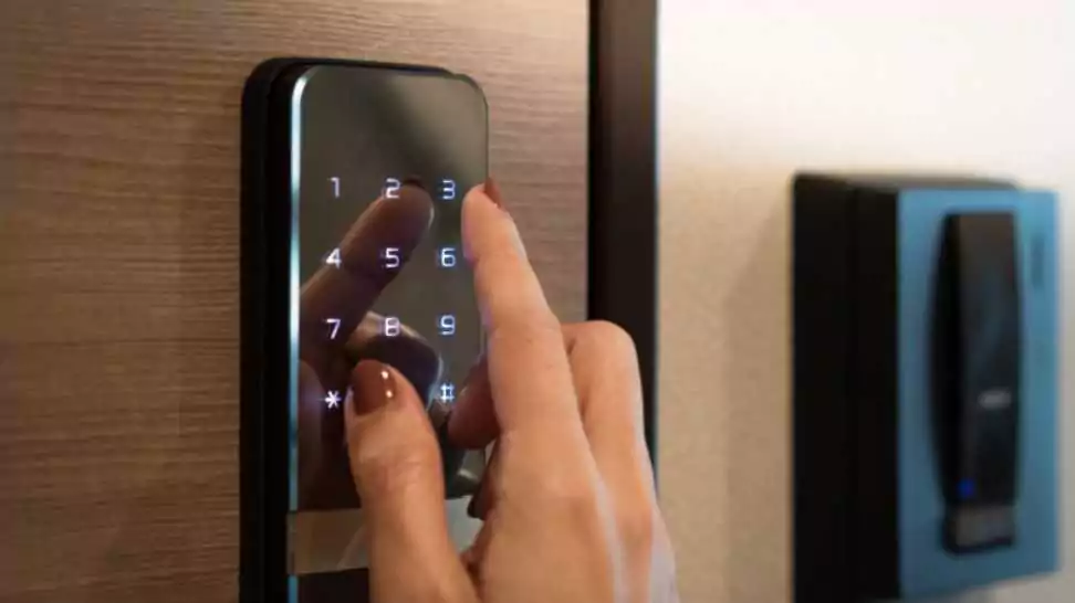 woman's finger entering password code on the smart digital touch screen keypad entry door lock in front of the room