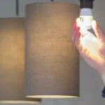 a man turning a lighted smart light bulb in his own new house