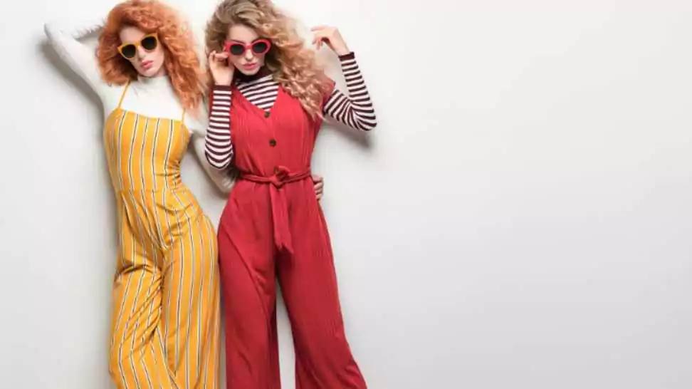 two girls in trendy glamor outfit with curly hairstyle gorgeous woman in red yellow jumpsuit
