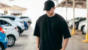 man wearing black blank oversized t shirt and a black baseball cap