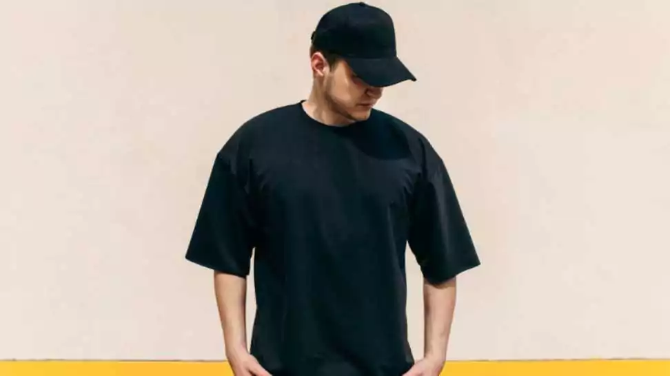 man wearing black blank oversized t shirt and a black baseball cap