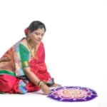portrait of maharashtrian woman making a rangoli in nauvari saree