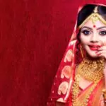 portrait of an elegant indian model in bridal look with heavy gold jewelry and red gujarati sari