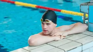 fit strong swimmer with a black swimming cap looking at the pool