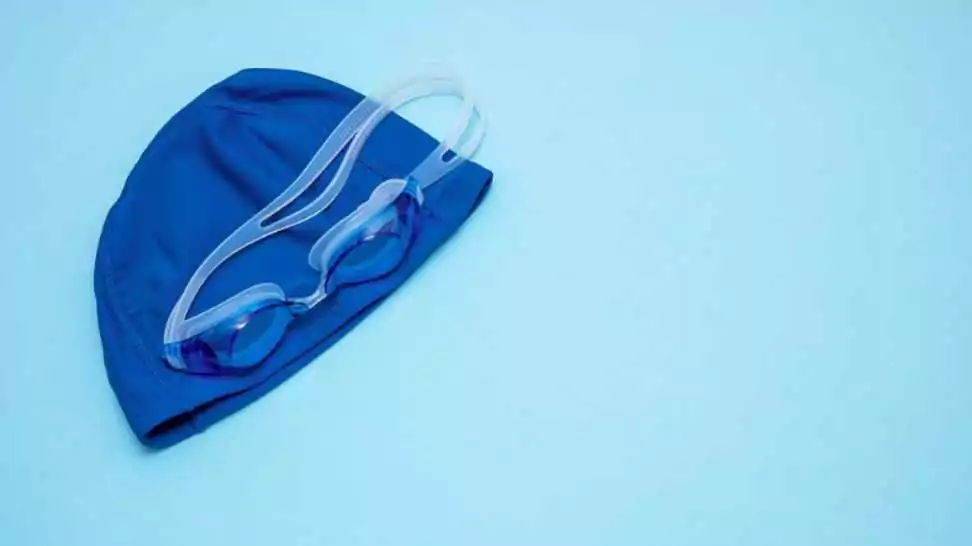swimming cap and goggles on a blue background