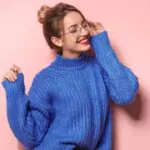 beautiful young woman in warm pullover sweater on color background