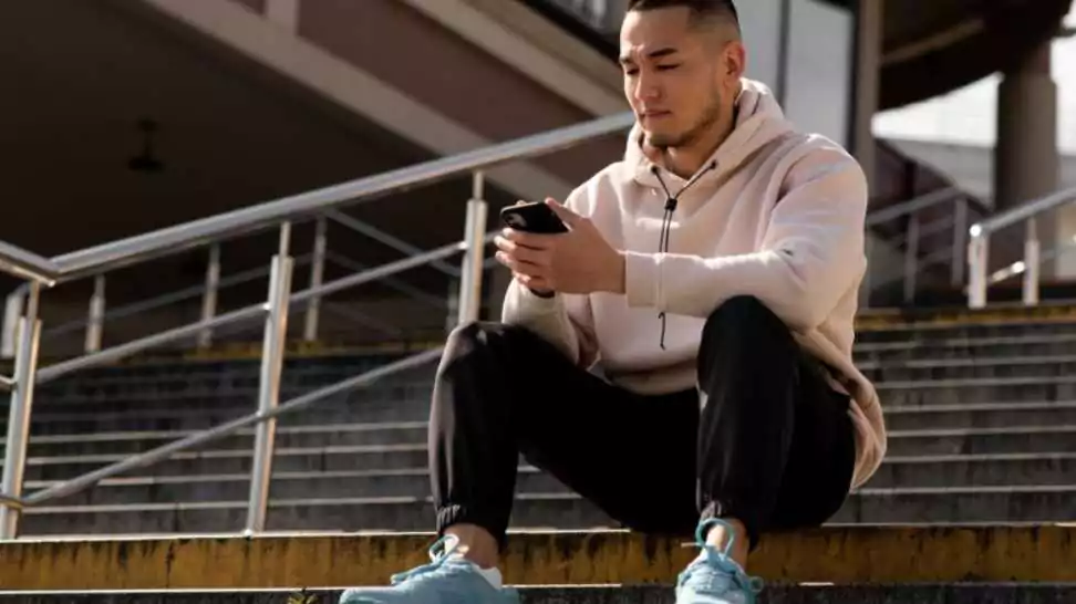 man sitting on stairs wearing a hoodie with joggers