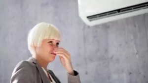 woman covering her nose from bad smell inside from ac